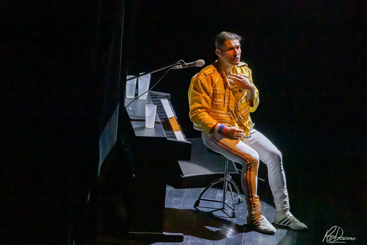 Thierry Margot au piano – Je Vis avec Freddie Mercury Thierry Margot assis près du piano, vêtu de la veste jaune de Freddie Mercury, sur la scène de L’Esty à Chavanod.